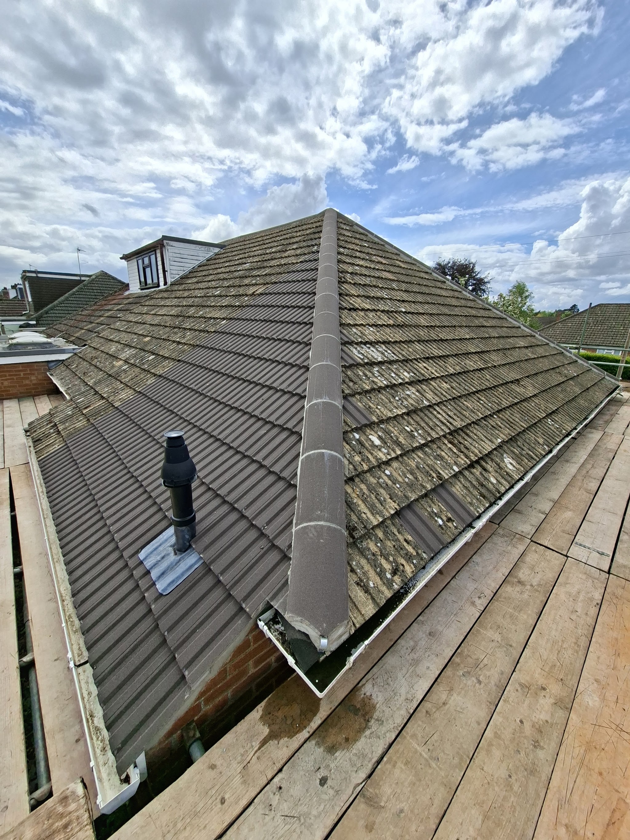 A concrete tiled roof with a new ridge, seen from the scaffold