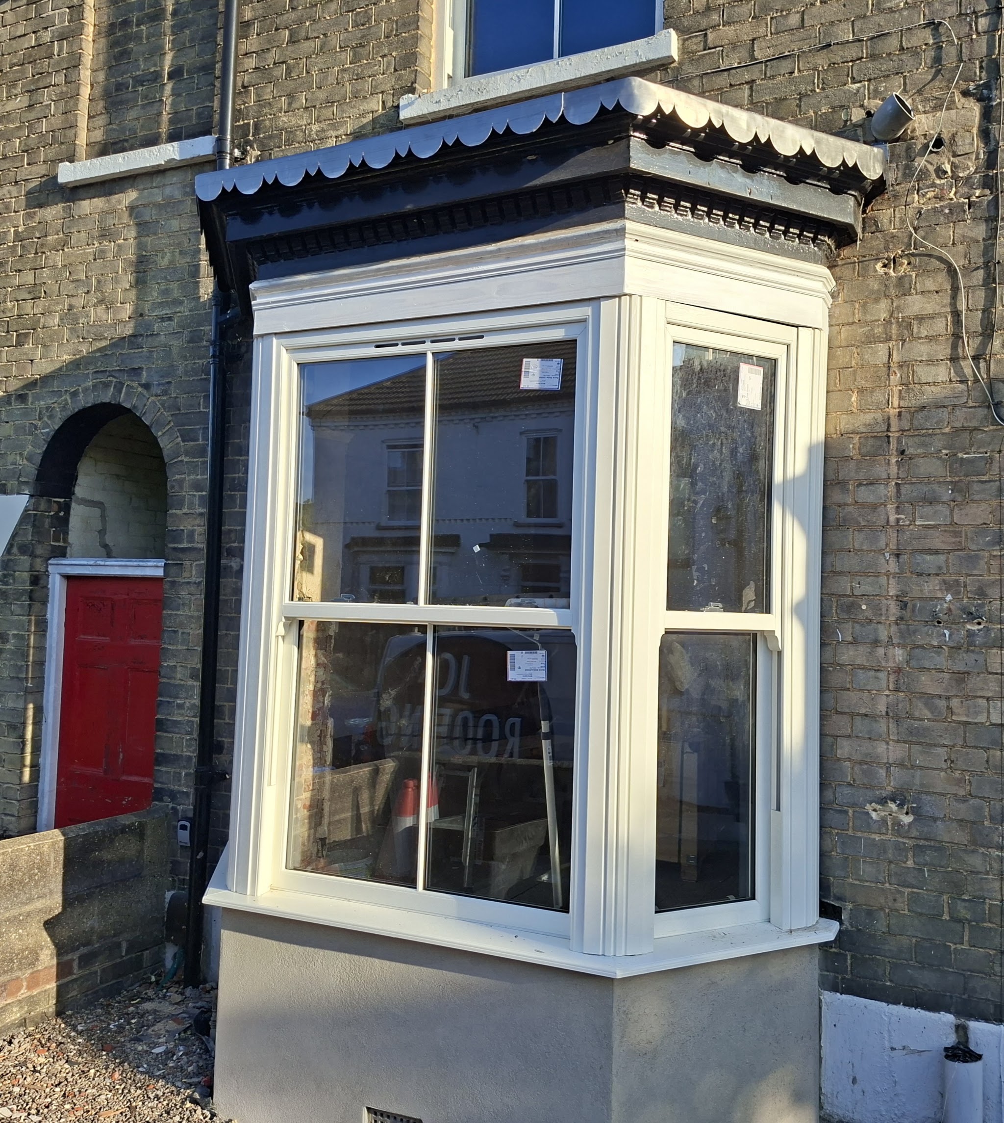 A finished bay window roof with a scalloped trim on a terraced house
