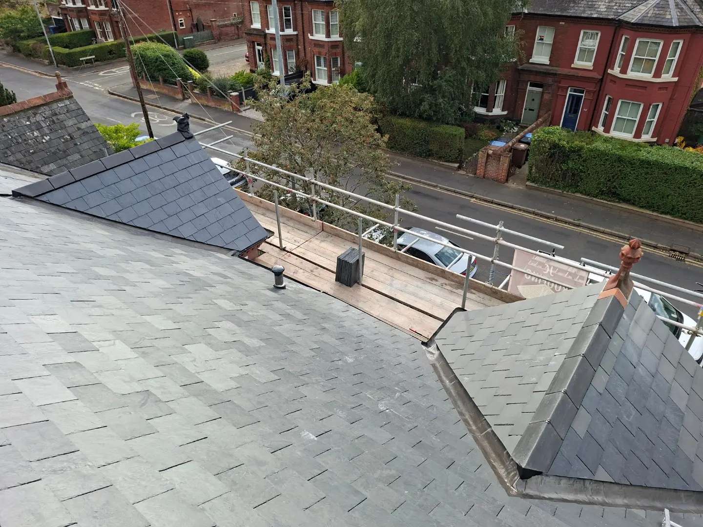 A newly slated roof seen from the scaffold, with the street below